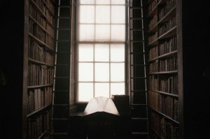 Dimly lit library with tall shelves full of books on both sides, showcasing the best books on forgiveness and letting go.